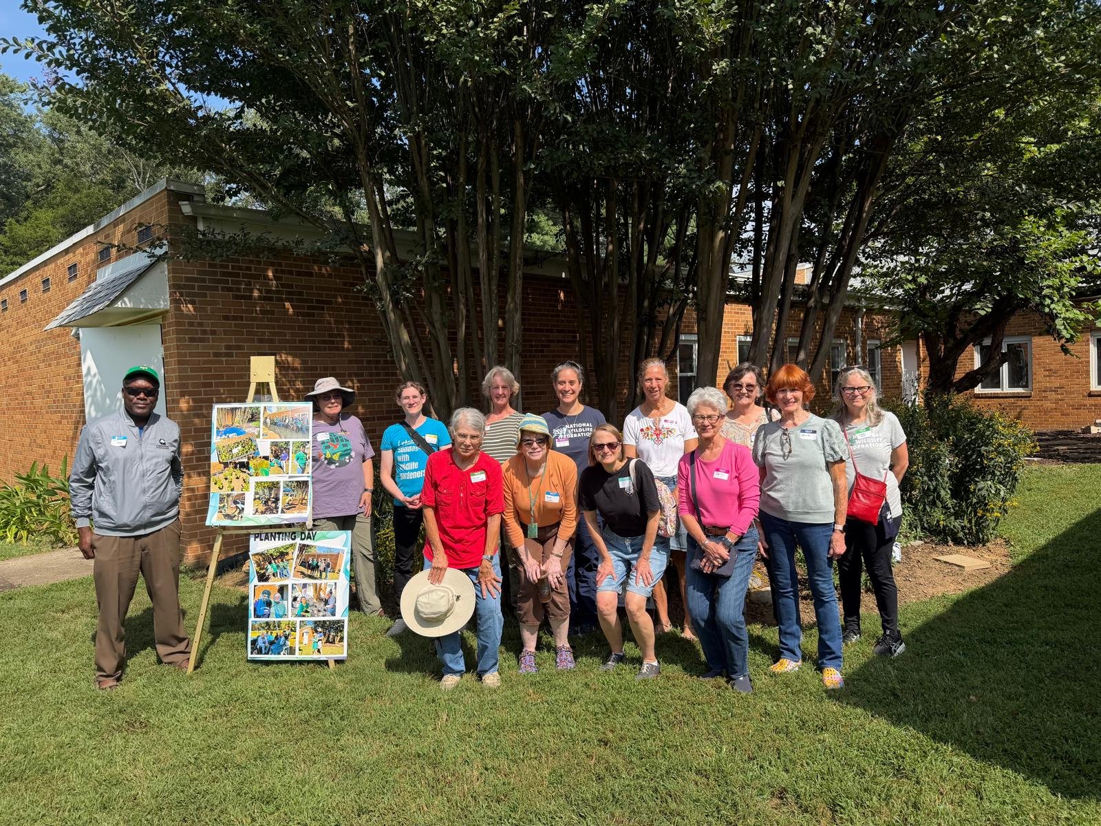 Tour attendees posing beside a native plant garden bed.